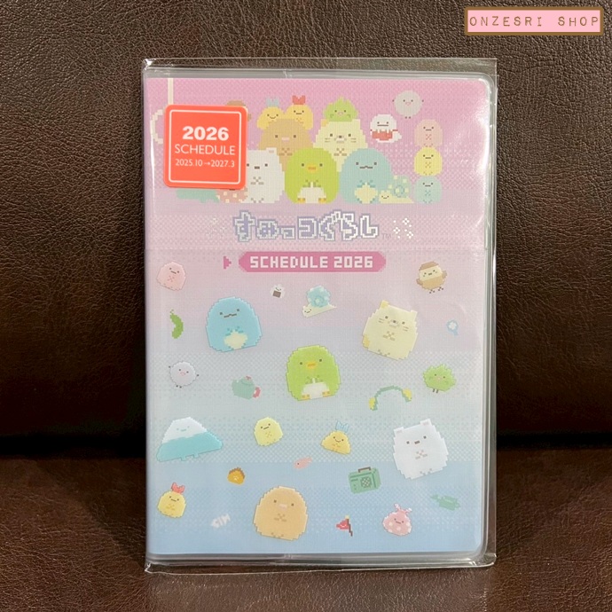 สมุด 2026 Schedule Book เล่มกลาง A6 ลาย Sumikko Gurashi สีชมพู ขนาด 10.8 x 15.5 x 0.6 ซม. (64 หน้า) มีให้จดตั้งแต่เดือน 10/2025 - 3/2027 เป็นปฎิทินแบบ monthly ช่องกลาง ด้านหน้าเป็นช่อง pocket ใส่ของได้
